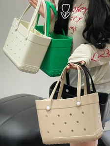 Detail of EVA beach tote bags in beige, green, and black with signature perforated holes