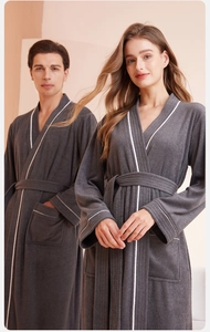 Detail of dark grey couple bathrobe with white piping and soft fleece texture