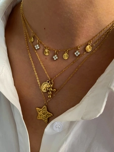 Close-up of layered gold necklaces with star, coin, and cross charms on model