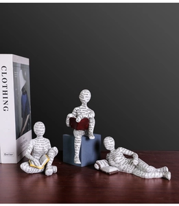 Vista dettagliata di tre figurine di lettori in resina bianca con tipografia artistica