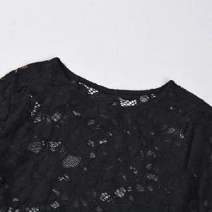 Détail du col rond sur haut en dentelle noire transparente avec motifs floraux complexes