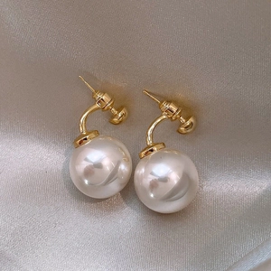 Elegant gold hook pearl earrings with large round pearls on champagne silk fabric