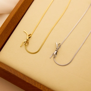 Colliers avec pendentif nœud en or et argent sur chaînes serpent plates sur un plateau
