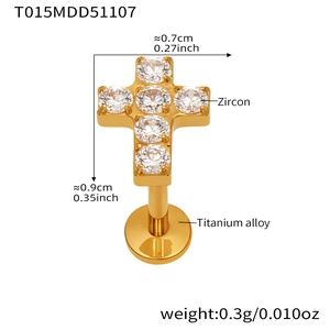 Detail view of a gold cross piercing made of titanium alloy with zircon inlay