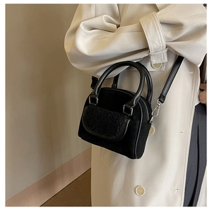 Detail view of the black plush textures and silver hardware on a crossbody handbag