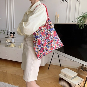 Detailed view of floral tote bag worn by model in a modern minimalist indoor setting
