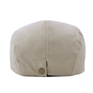 Détail du tissu en sergé de coton beige et du bouton métallique sur une casquette
