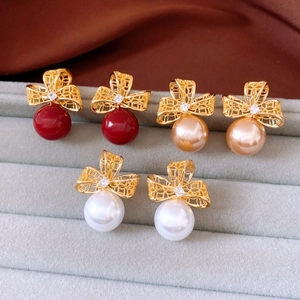 Détail de boucles d'oreilles nœuds plaquées or 18 carats en rouge, champagne et blanc