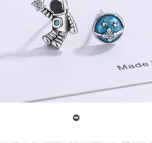 Close-up of asymmetric astronaut and blue planet stud earrings with crystal accents