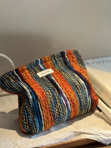 Detailaufnahme der gewebten Boho-Kosmetiktasche mit bunten Streifen und Markenlogo