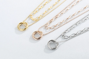 Close-up of triple-ring pendant necklaces in gold, silver, and rose gold finishes