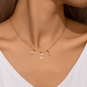 Detail of gold S925 sterling silver necklace with heart and gem charms on a model