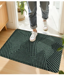 Detail der grünen geometrischen PVC-Türmatte im Eingangsbereich mit weißen Segeltuchschuhen