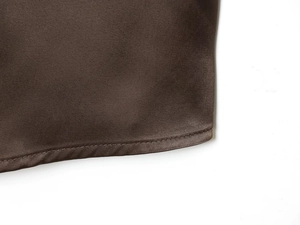 Detail of double-stitched hem on dark brown satin fabric with a smooth silk finish