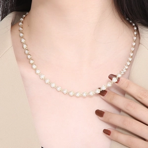 Close-up of elegant gold heart chain necklace on model with beige suit and锁骨 focus
