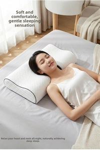 Ergonomic white memory foam pillow with blue piping and massage texture shown on a bed