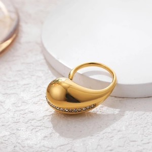 Detail of gold pear-shaped ring featuring clear zircon stone accents on white base