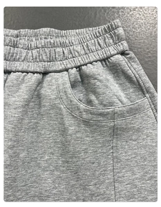 Close-up of elastic waistband and side pocket detail on grey cotton track pants