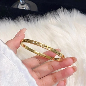 Close-up of gold-plated titanium bracelet featuring Roman numerals and cubic zirconia