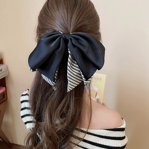 Détail d'un nœud papillon en soie noire avec rubans rayés et perles sur cheveux