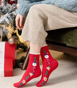 Detail of red Christmas socks with cartoon Santa Claus and reindeer embroidery
