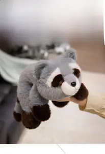 Detail view of a soft plush raccoon toy with grey and brown fur held in hand