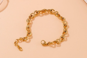 Detail view of gold infinity necklace with adjustable lobster clasp on warm apricot background