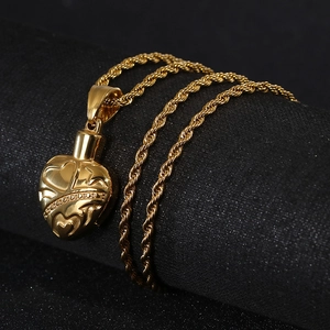 Close-up of gold heart pendant necklace with relief patterns on a dark background