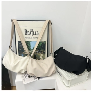 Minimalist pleated dumpling crossbody bags in white, beige and black displayed together
