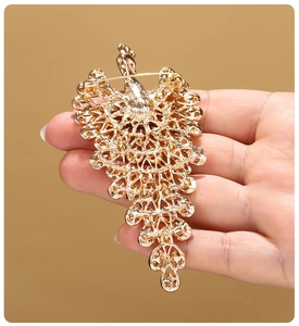 Detail showing back of gold peacock brooch with pin fastener and openwork metal craft