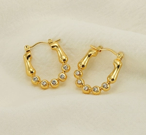 Detail of 18K gold-plated bamboo-style hoop earrings with sparkling zircon accents