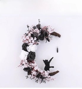 Detail of moon-shaped wreath with black roses, a black cat silhouette and crystal pendant