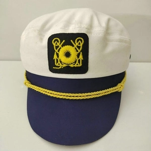 Detail of white nautical captain hat with gold anchor embroidery and braided rope cord