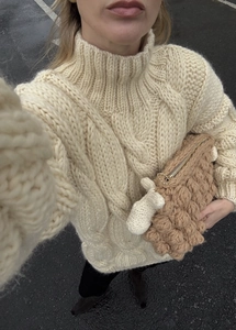 Detail of cable knit pattern and thick turtleneck texture on cream white sweater