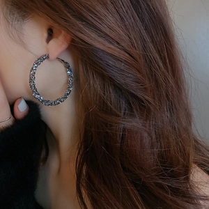 Macro side view of a large gunmetal hoop earring with pavé rhinestones on a female model