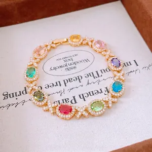 Elegante bracciale in oro con gemme ovali multicolori e fibbia a croce in vista a 45 gradi