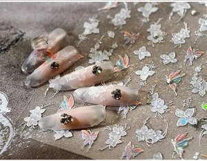 Macro shot of iridescent butterfly and white floral lace nail art stickers on clear tips