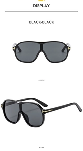 Detail of oversized pilot sunglasses with black frames and iconic metal T-hinge accents