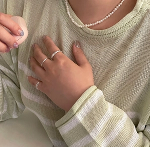 Detailed view of 925 sterling silver knotted rings worn with striped knitwear and pearls