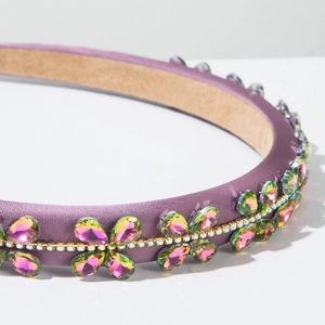 Detail of baroque headband with colorful floral rhinestones on purple satin fabric