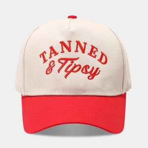 Detail of red and cream baseball cap featuring TANNED & Tipsy embroidered text