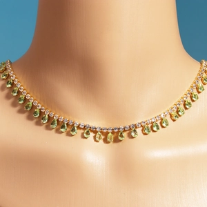 Detail of gold plated necklace featuring light green pear cut zircon tassel charms