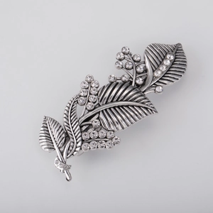 Detail shot of vintage silver leaf hair clip with intricate textures and small white rhinestones