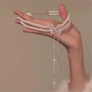 Gros plan d'un collier ras du cou en perles double rang avec pendentif papillon brillant