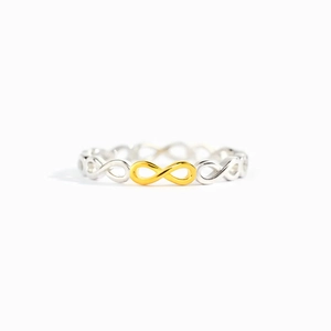 Minimalist S925 sterling silver infinity ring with a gold-tone symbol on a white background