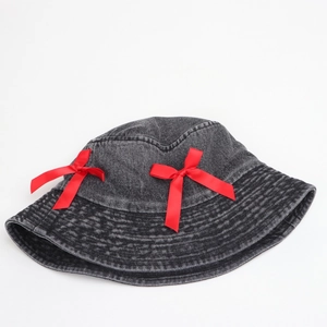 Detail of red satin bows on black washed denim bucket hat with retro aesthetic