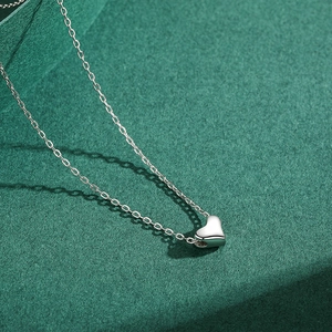 Minimalist S925 sterling silver heart pendant necklace on dark green textured background