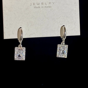 Macro shot of silver micro-pave zircon earrings with emerald-cut crystals on black background
