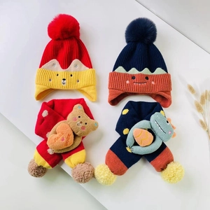 Detail of knit hats and scarves featuring 3D plush bear and dinosaur decorations