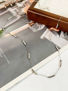 Detail of silver geometric square bead necklace on a lifestyle background